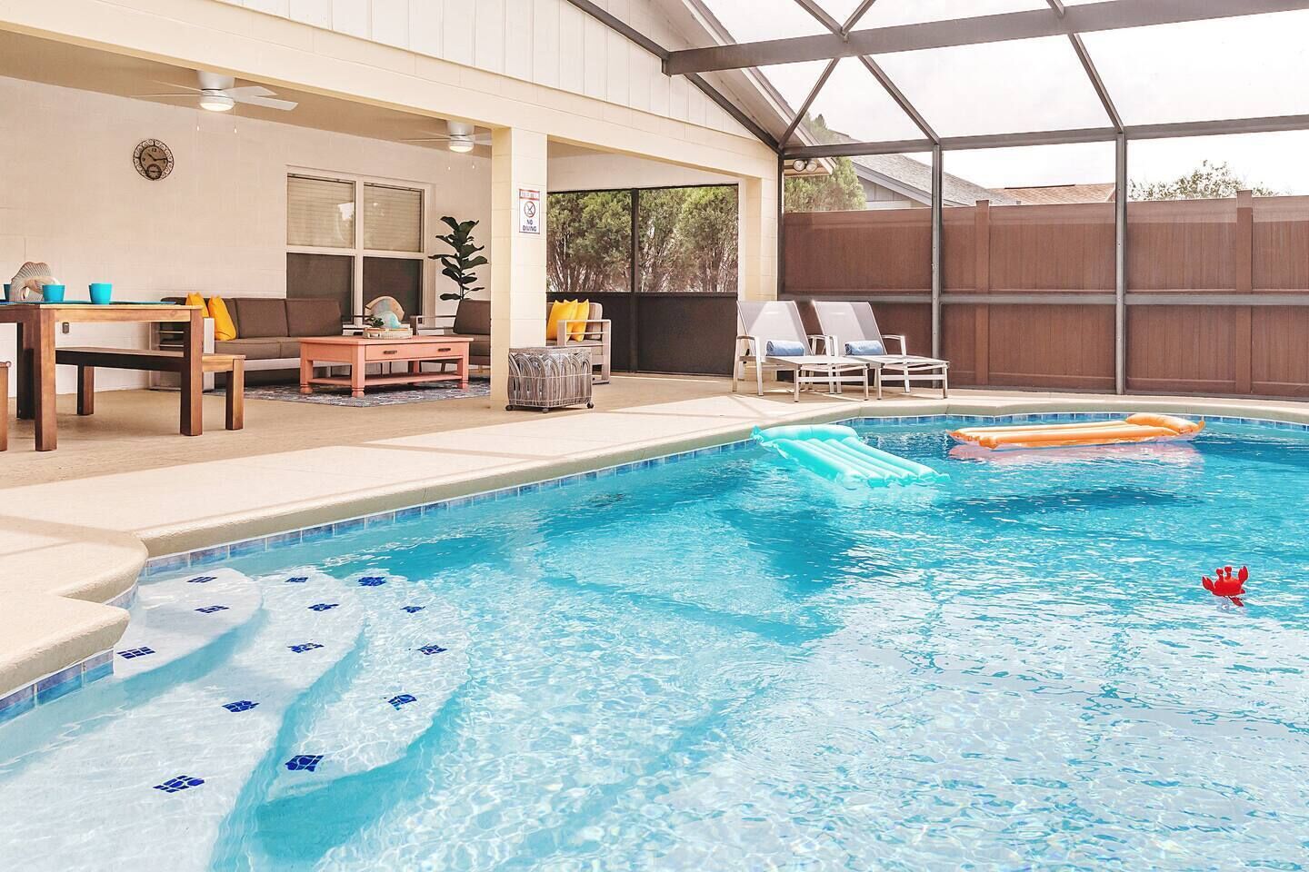 A swimming pool with a hot tub, lounge chairs, and a table with chairs.