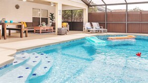 A swimming pool with a hot tub, lounge chairs, and a table with chairs.