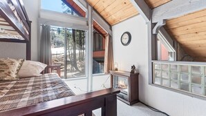 Quarto com cama, lareira, relógio e uma janela grande.