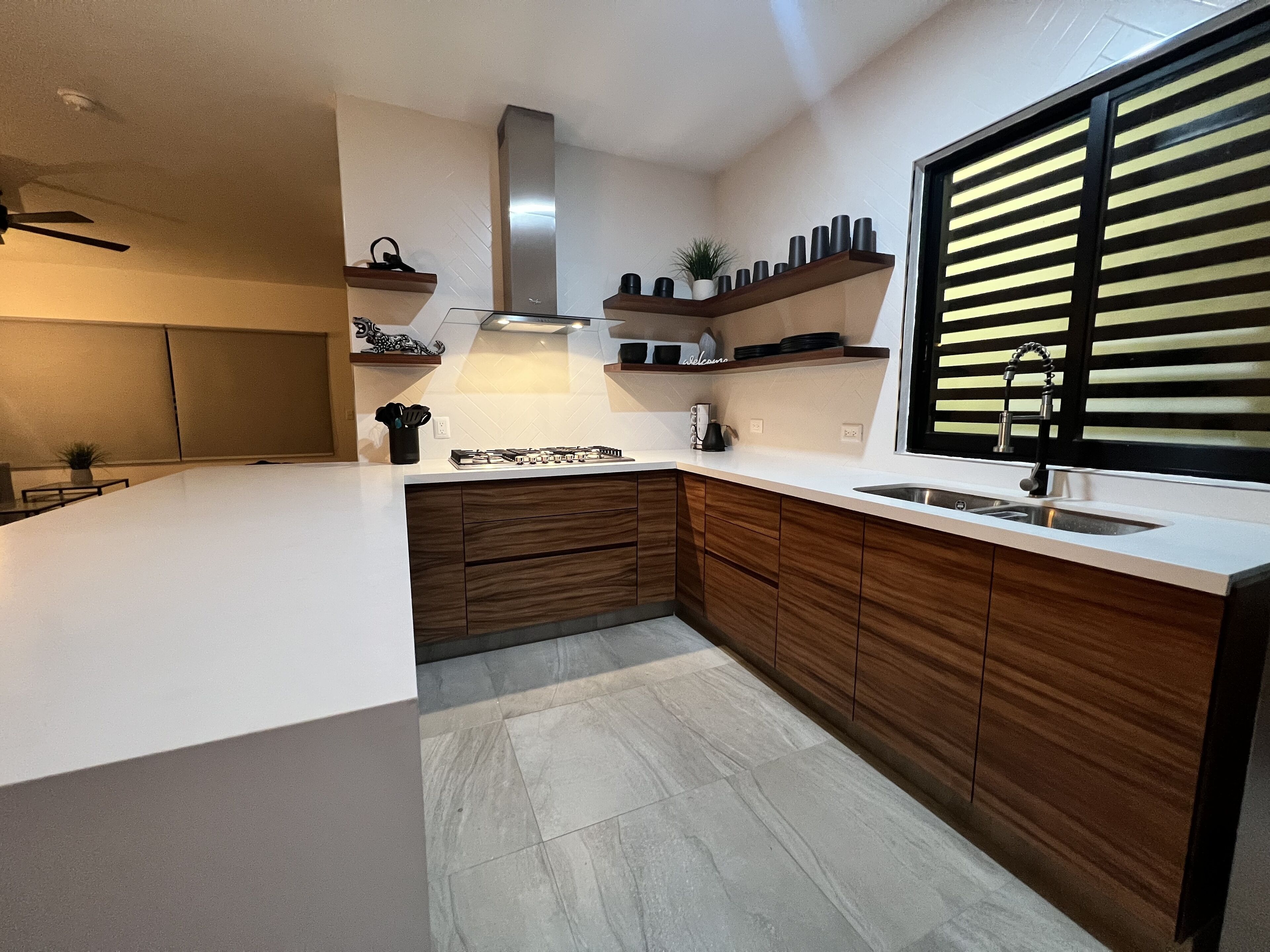 Une cuisine moderne dotée d’un grand îlot central, de meubles en bois et d’une hotte de cuisine en acier inoxydable.