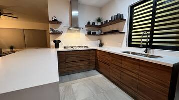 Une cuisine moderne dotée d’un grand îlot central, de meubles en bois et d’une hotte de cuisine en acier inoxydable.