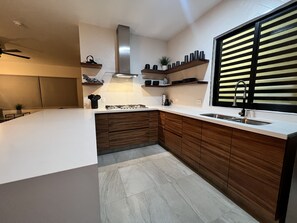 A modern kitchen with a large island, wooden cabinets, and a stainless steel range hood.