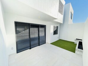 A modern house with a large sliding door, a small lawn, and a white exterior.
