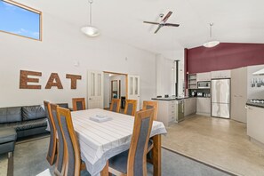 A modern kitchen with a dining area, a ceiling fan, and a large window.