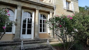 A stately building with arched windows, a balcony with a wrought iron railing, and a stone staircase leading to the entrance.