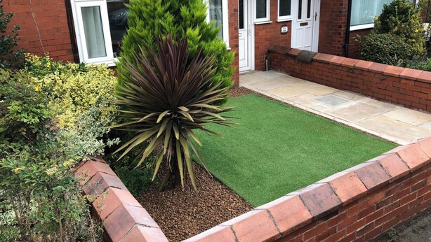 A residential garden with a lawn, a large plant, and a brick wall. - House - Sleeps 5 - Pet Friendly - West Facing Enclosed Rear Garden - On Street Parking (Lytham St. Anne's)