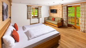 A room with a large bed, a sofa, a TV, and a window with curtains. - Vacation apartment Watzmo, 1-3 persons, 50 sqm, balcony, separate bedroom (Ramsau bei Berchtesgaden)