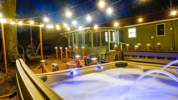 A hot tub area with string lights and a covered seating area.