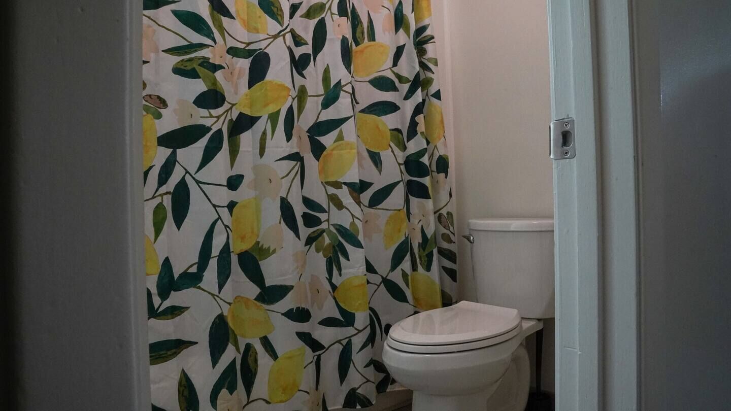 Ein Badezimmer mit Toilette und einer blumigen Duschvorhang.