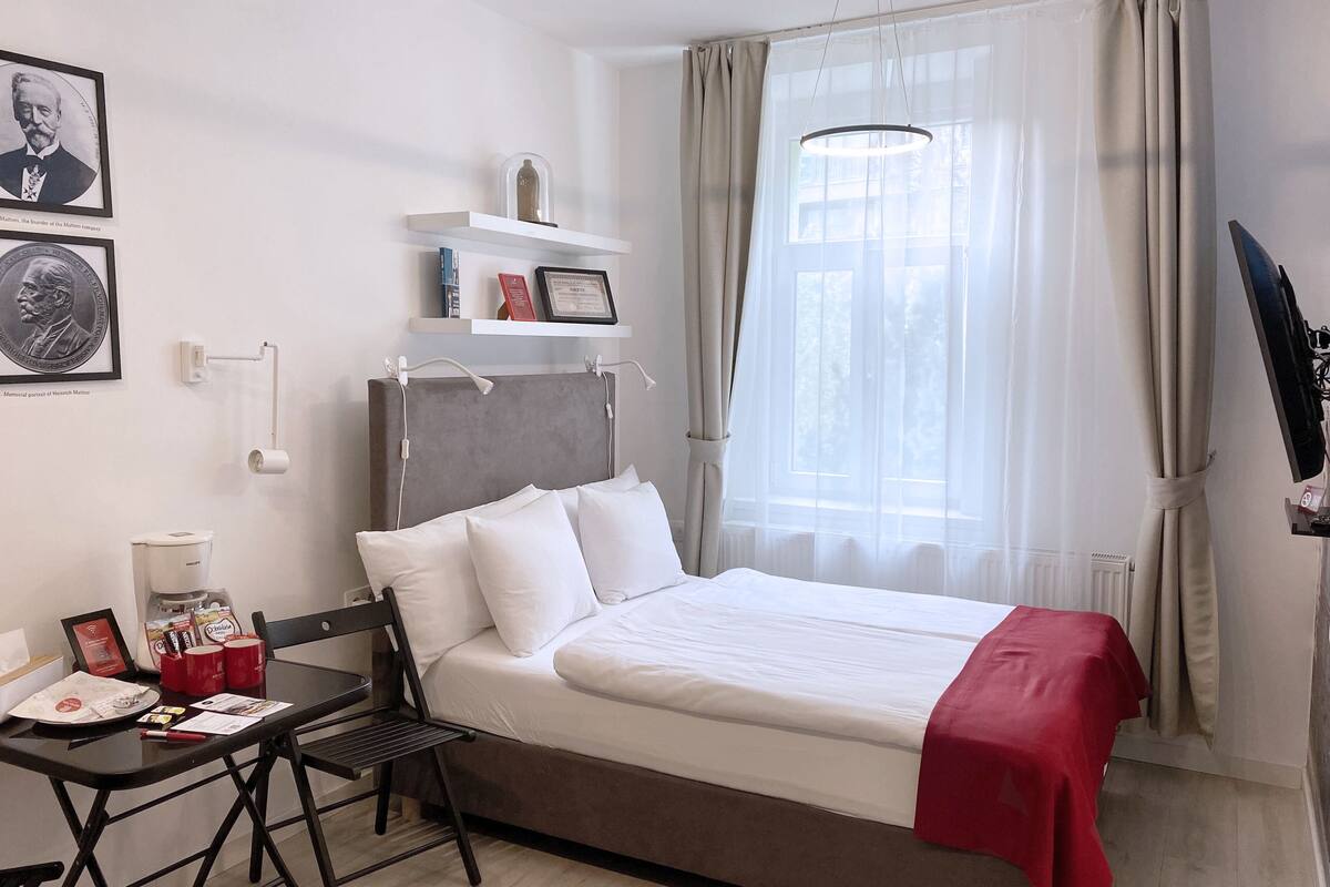 Hotellihuone, jossa on sänky, työpöytä, tuoli, kahvinkeitin ja televisio.