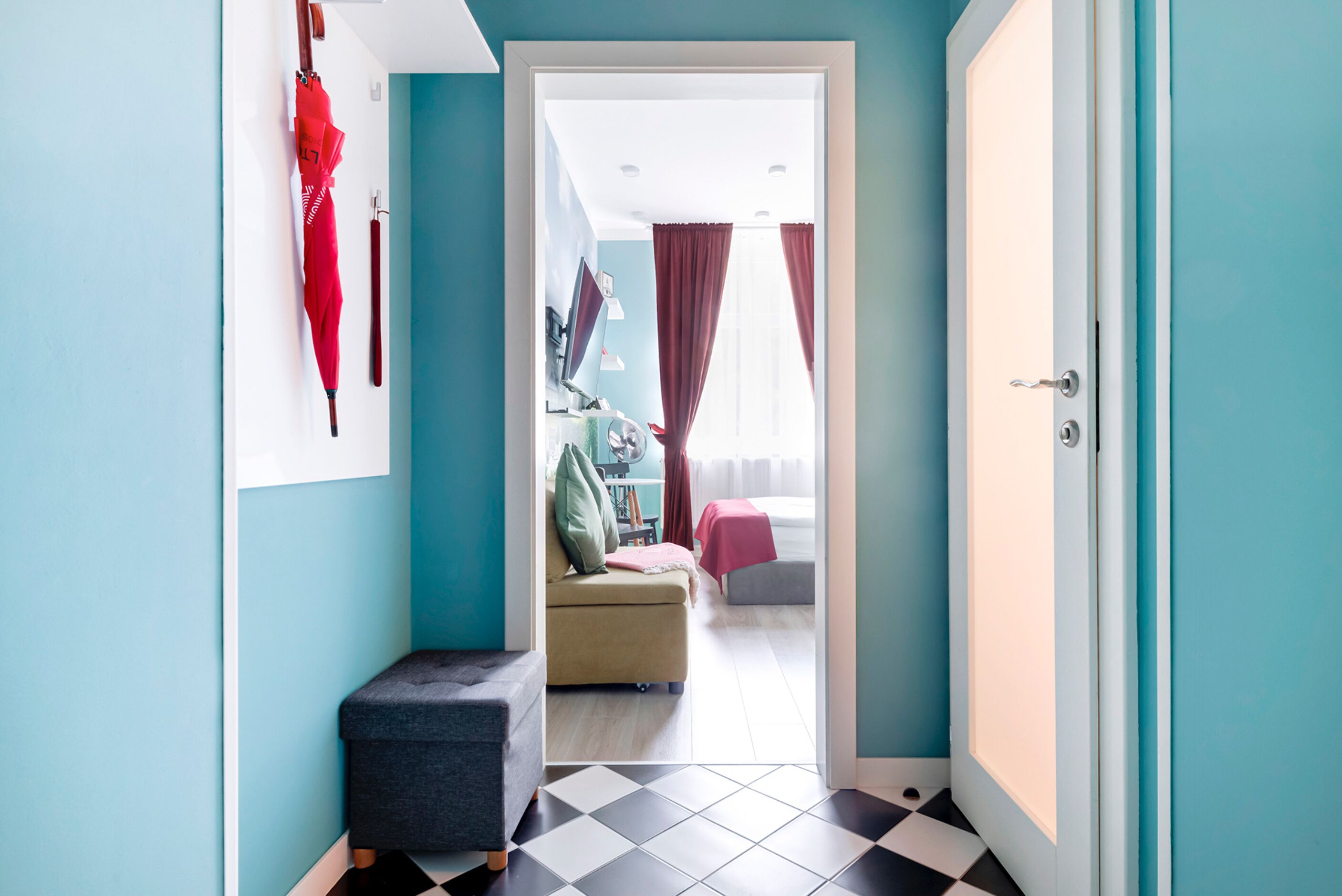 Un pasillo que conduce a un dormitorio con una cama, una silla y una mesita.