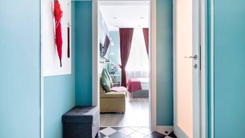 Un pasillo que conduce a un dormitorio con una cama, una silla y una mesita.