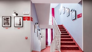 A staircase with red carpet leading to a landing with framed pictures and a sign indicating 'Studies'. - Revelton Studios Prague (Prague)