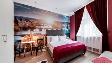 A hotel room with a large mural of a cityscape, a bed with a red blanket, a desk with a chair, and a window with red curtains.