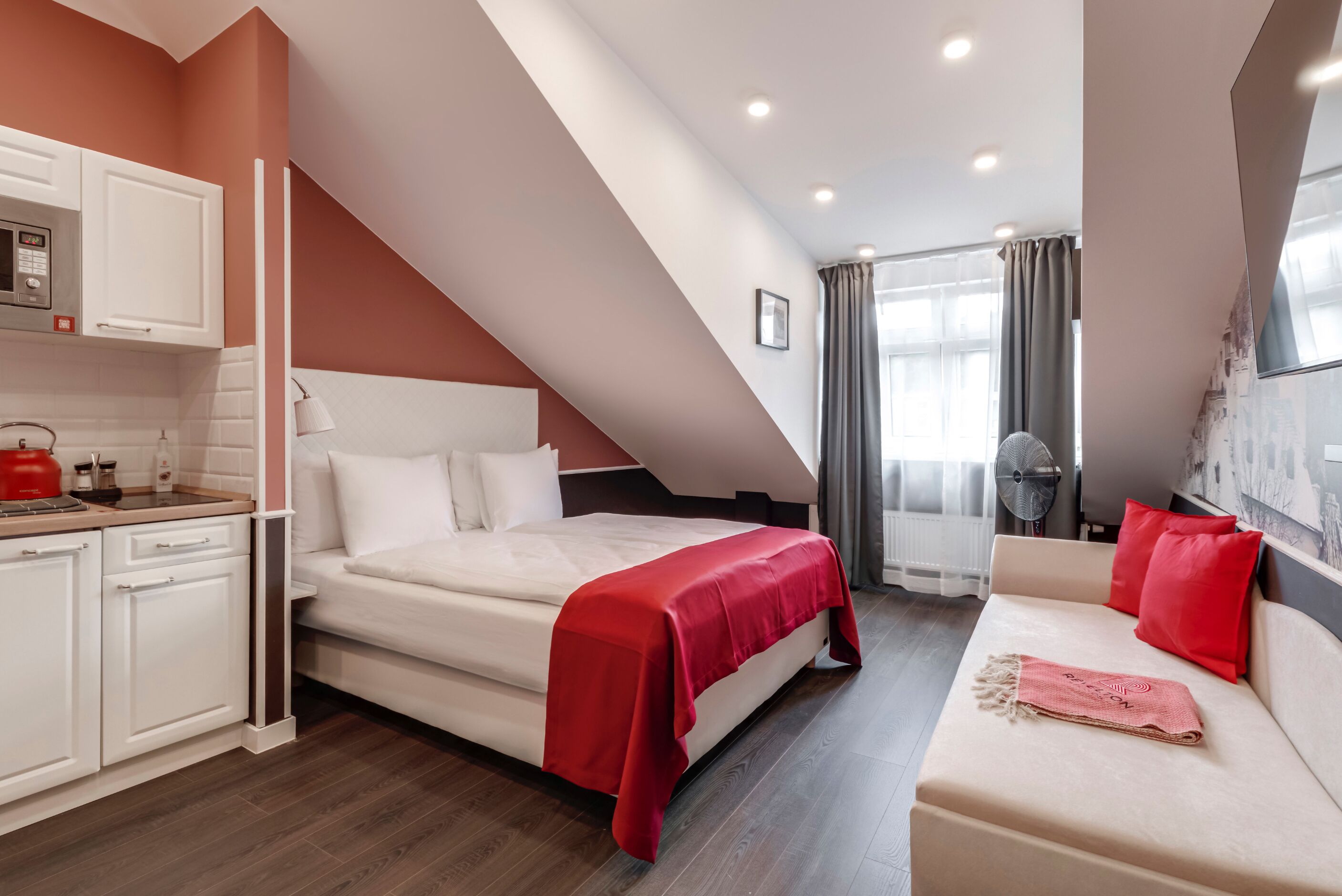 Un dormitorio moderno con cama, sofá, zona de cocina y mesa de comedor.