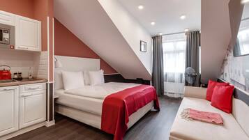Un dormitorio moderno con cama, sofá, zona de cocina y mesa de comedor.