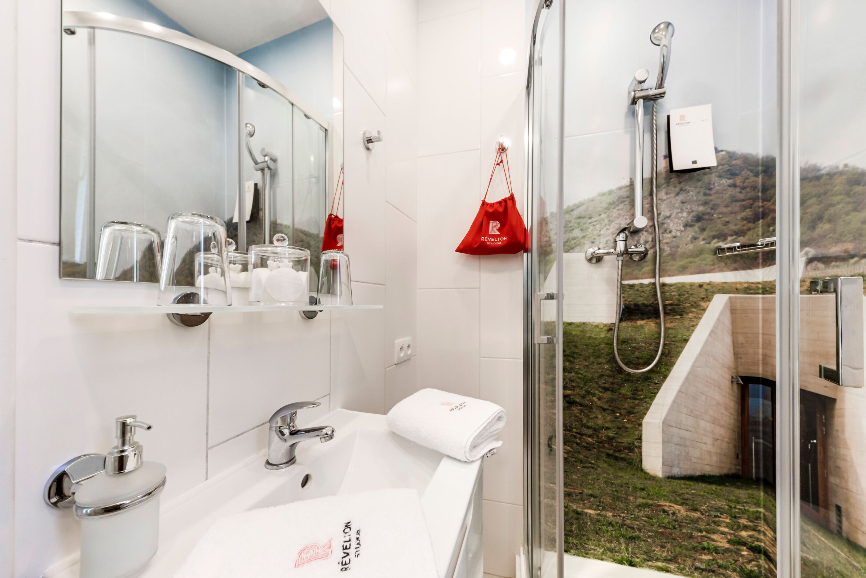 Un baño moderno con cabina de ducha de vidrio, un lavabo blanco y un espejo sobre el lavabo.