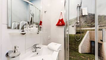 Un baño moderno con cabina de ducha de vidrio, un lavabo blanco y un espejo sobre el lavabo.