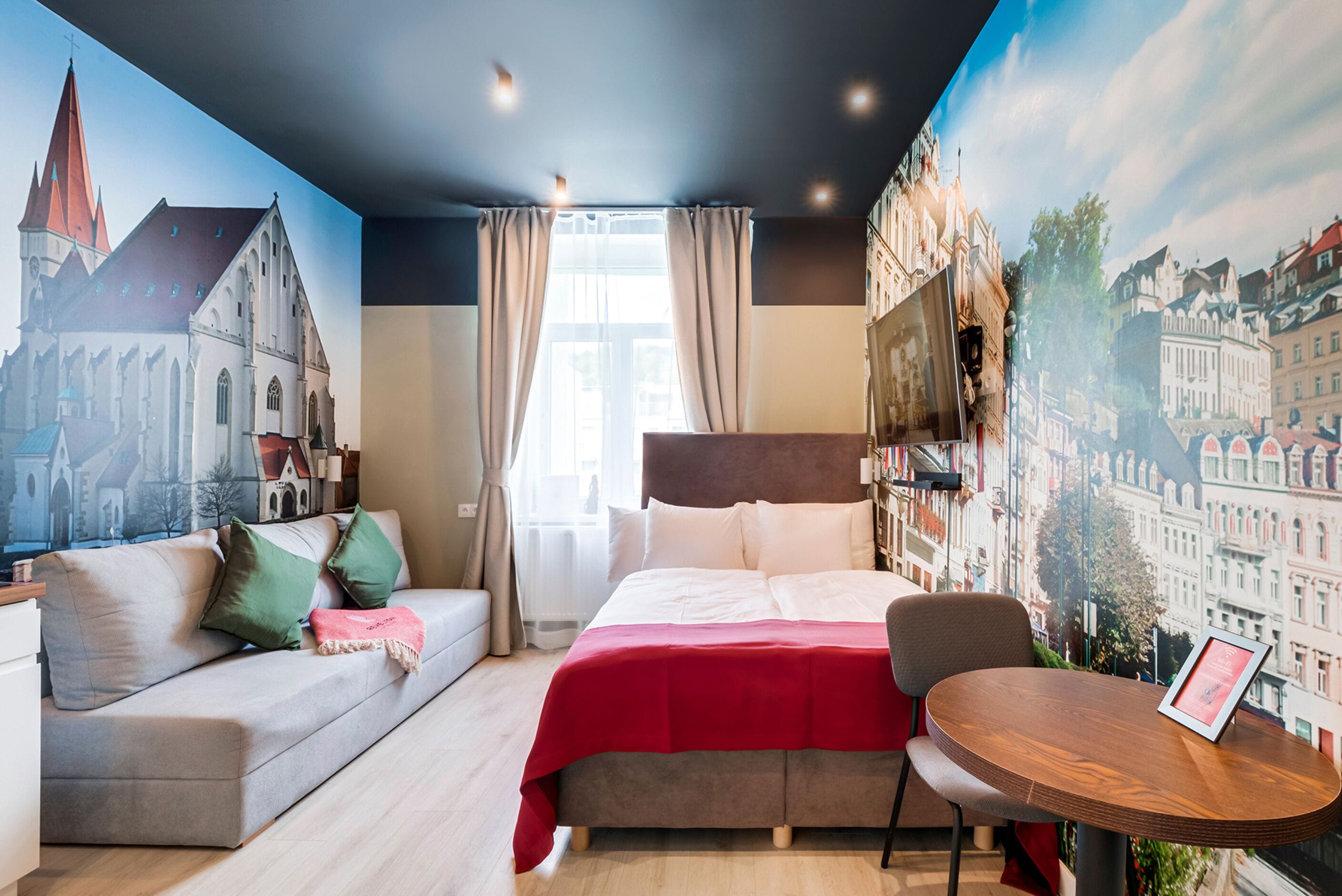 Una habitación de hotel con una cama, un sofá, una mesa de comedor y un mural de un paisaje urbano.
