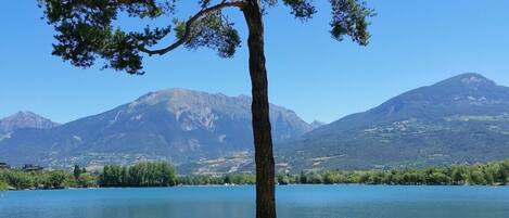 A wooden dock leading to a calm lake with mountains in the background.