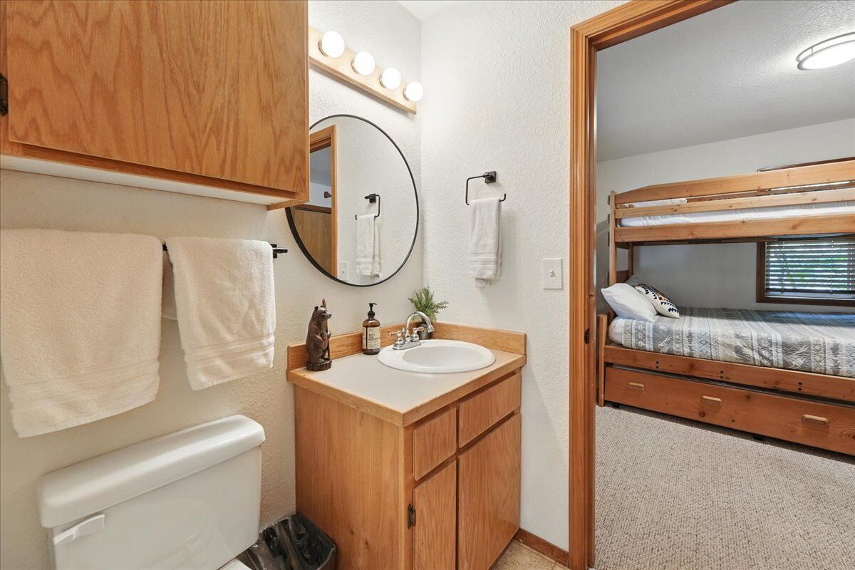 Une petite salle de bain avec un meuble-lavabo en bois, un miroir rond et un lavabo.