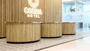 A hotel reception area with a wooden design and a sign that reads "CORDIA HOTEL". - Cordia Hotel Banjarmasin - Hotel Dalam Bandara (Banjarbaru)