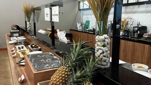 A buffet area with a variety of fruits like pineapples and a watermelon, and a coffee station. - Cordia Hotel Banjarmasin - Hotel Dalam Bandara (Banjarbaru)
