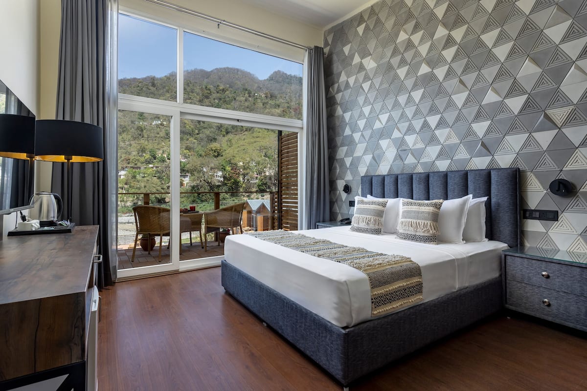 Een slaapkamer met een groot bed, een bureau en uitzicht op een balkon.