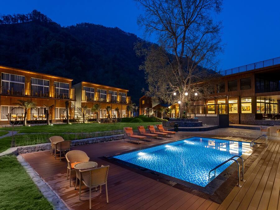 Un hotel moderno con piscina, area salotto esterna e terrazza ben illuminata.