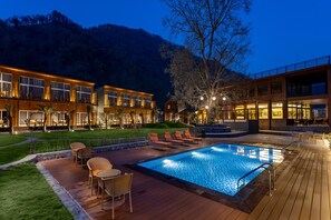 Un hôtel moderne doté d’une piscine, d’un espace extérieur aménagé et d’une terrasse bien éclairée.