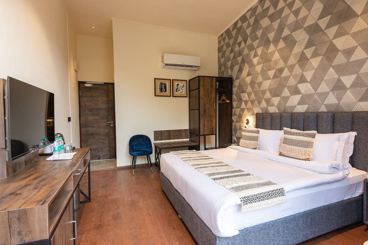 Een moderne hotelkamer met een groot bed, een bureau, een kledingkast en een flatscreen-televisie.