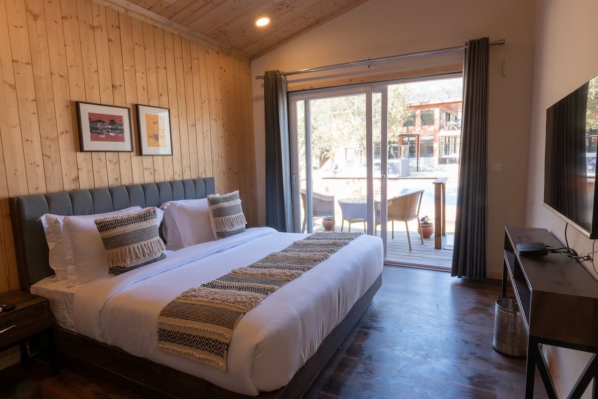 Een hotelkamer met een groot bed, een bureau en uitzicht op het balkon.