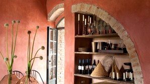 Un intérieur agrémenté d’une arche en briques, d’étagères remplies de bouteilles de vin et d’un vase avec des plantes.