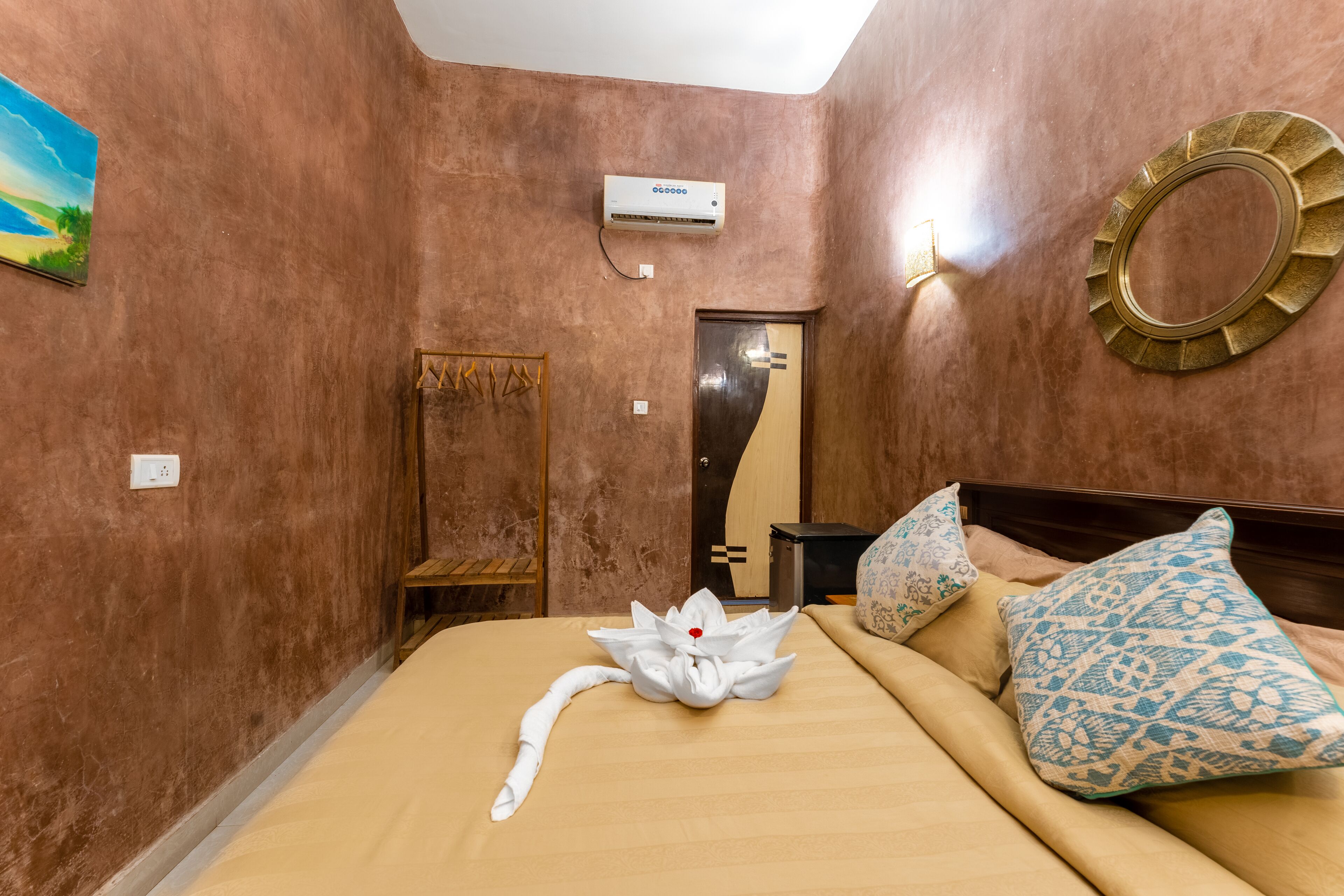 Habitación de hotel con cama, aire acondicionado de pared, espejo y un adorno en la pared.