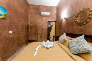 Habitación de hotel con cama, aire acondicionado de pared, espejo y un adorno en la pared.