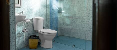 Un baño con inodoro, lavabo y cabina de ducha.