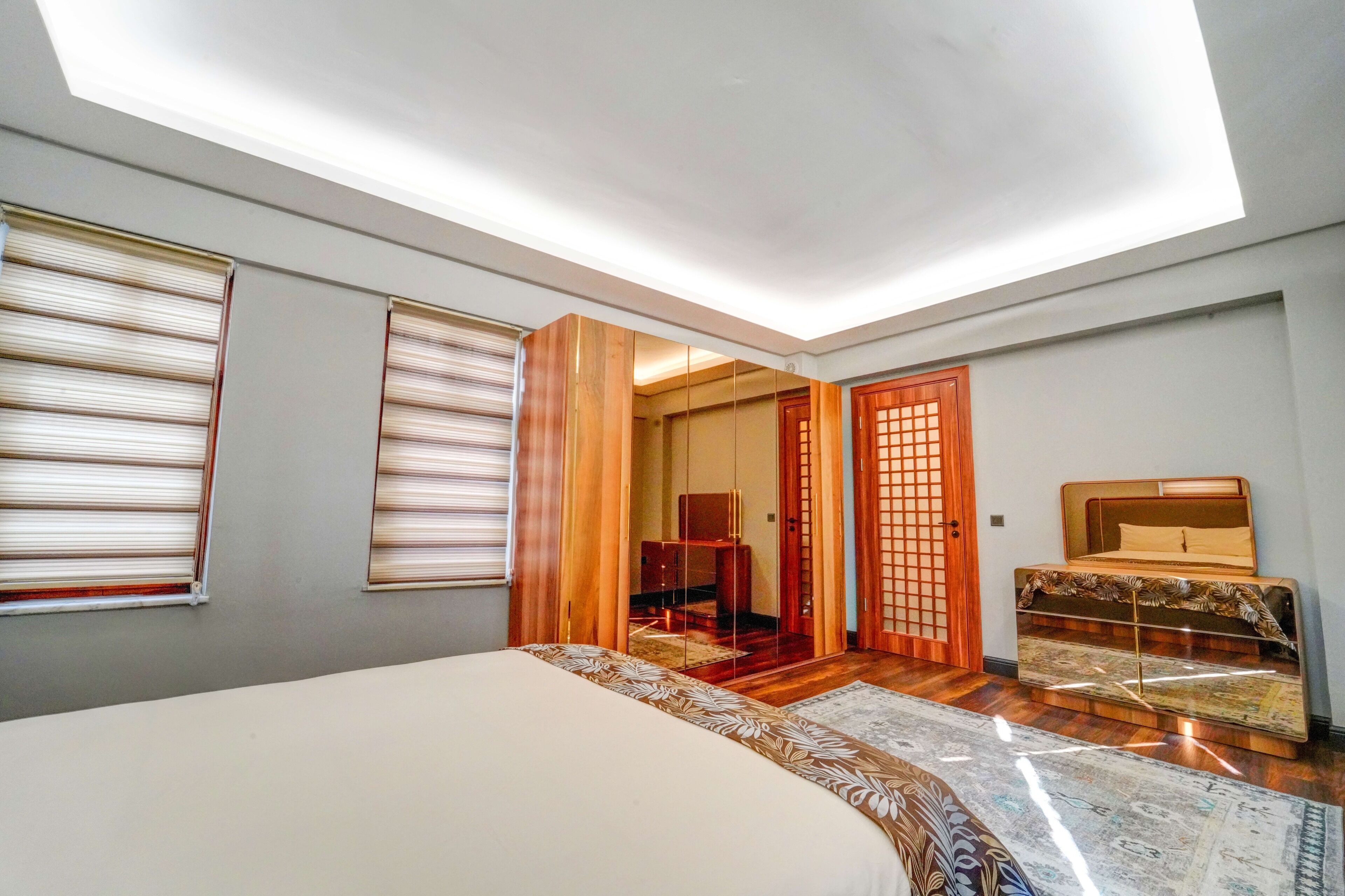 A bedroom with a bed, a wooden dresser, and a sliding door leading to another room.