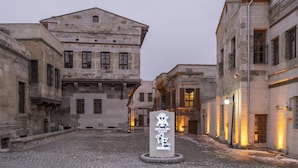 Un edificio histórico de piedra con un patio central, que presenta un panel informativo con inscripciones.