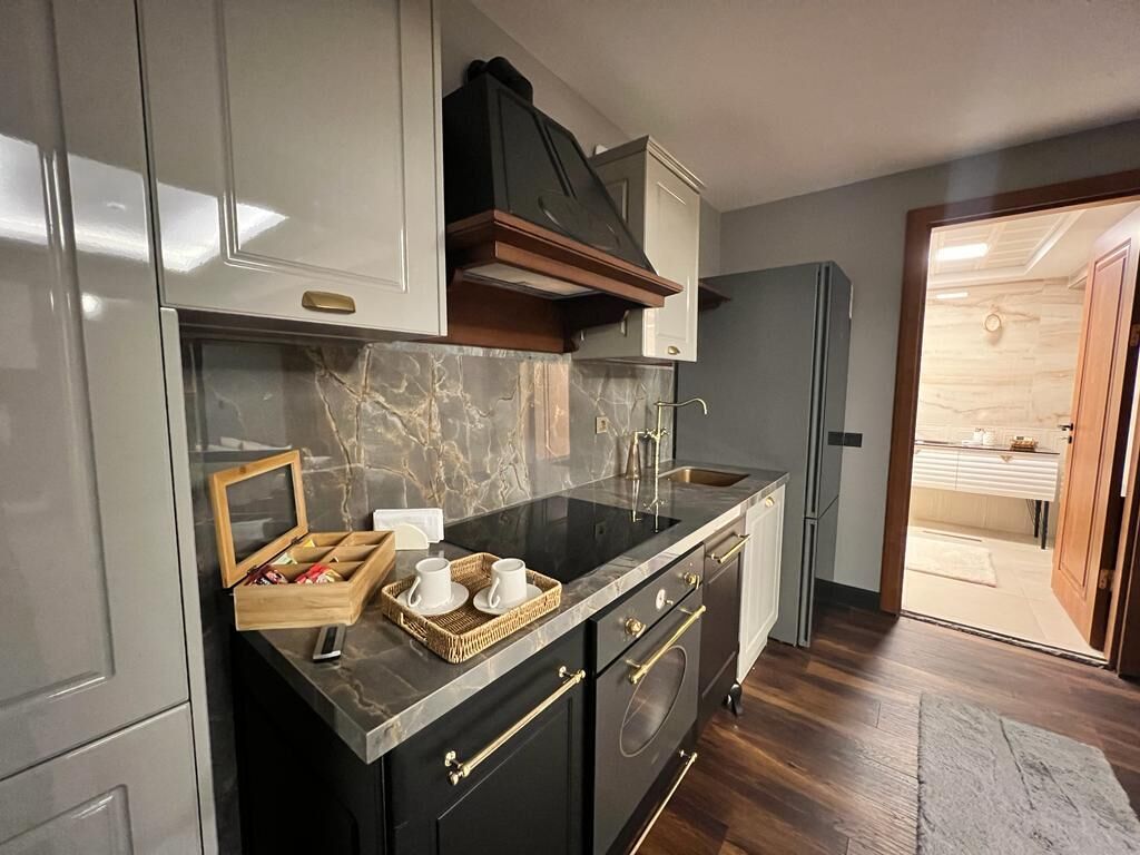 A modern kitchen with marble countertops, a built-in oven, and a wooden cabinet.