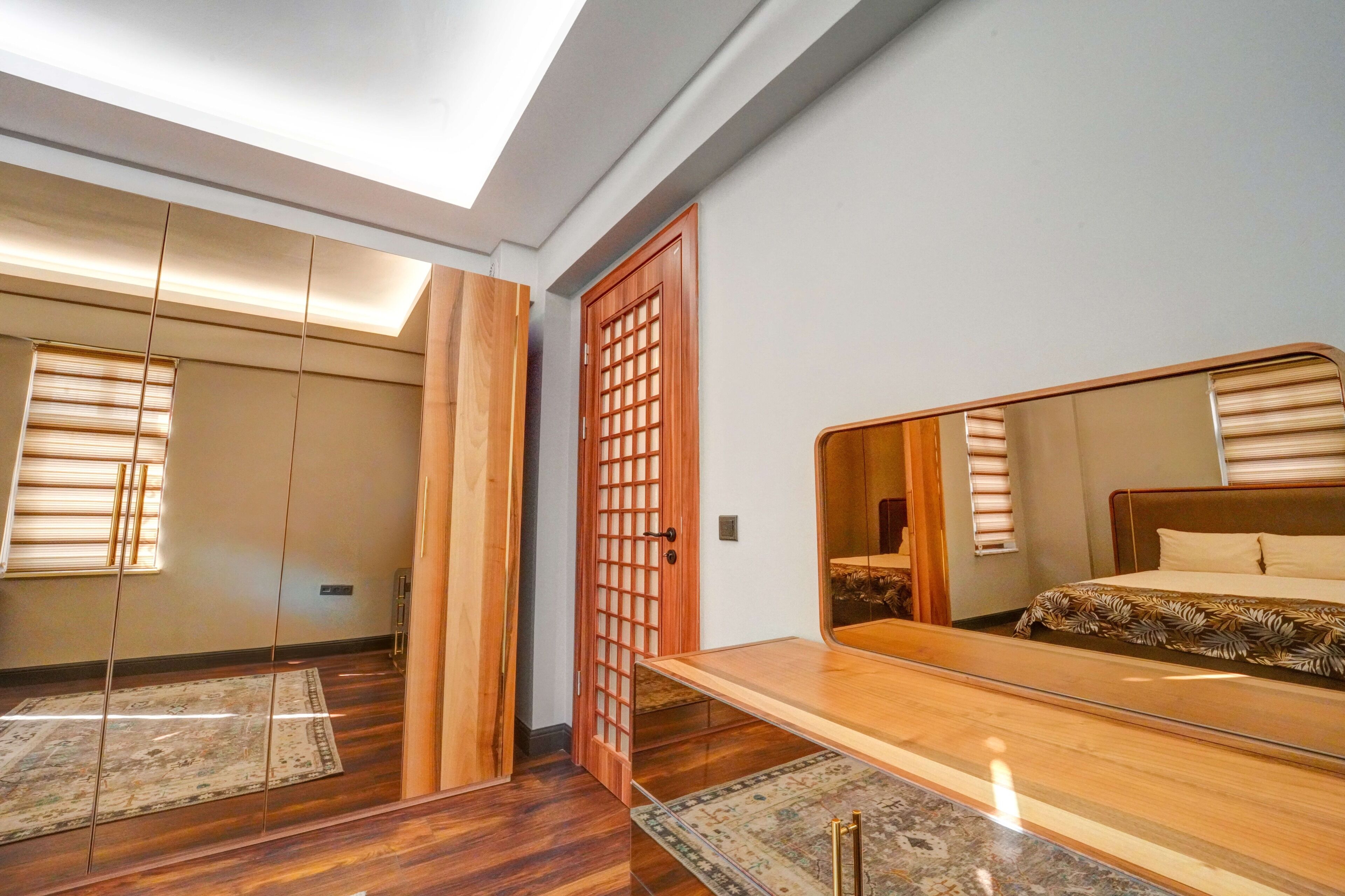 A bedroom with a large mirror, wooden flooring, and a traditional sliding door.