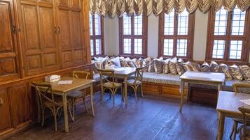 Una habitación con paneles de madera, un banco con cojines y una mesa con sillas.