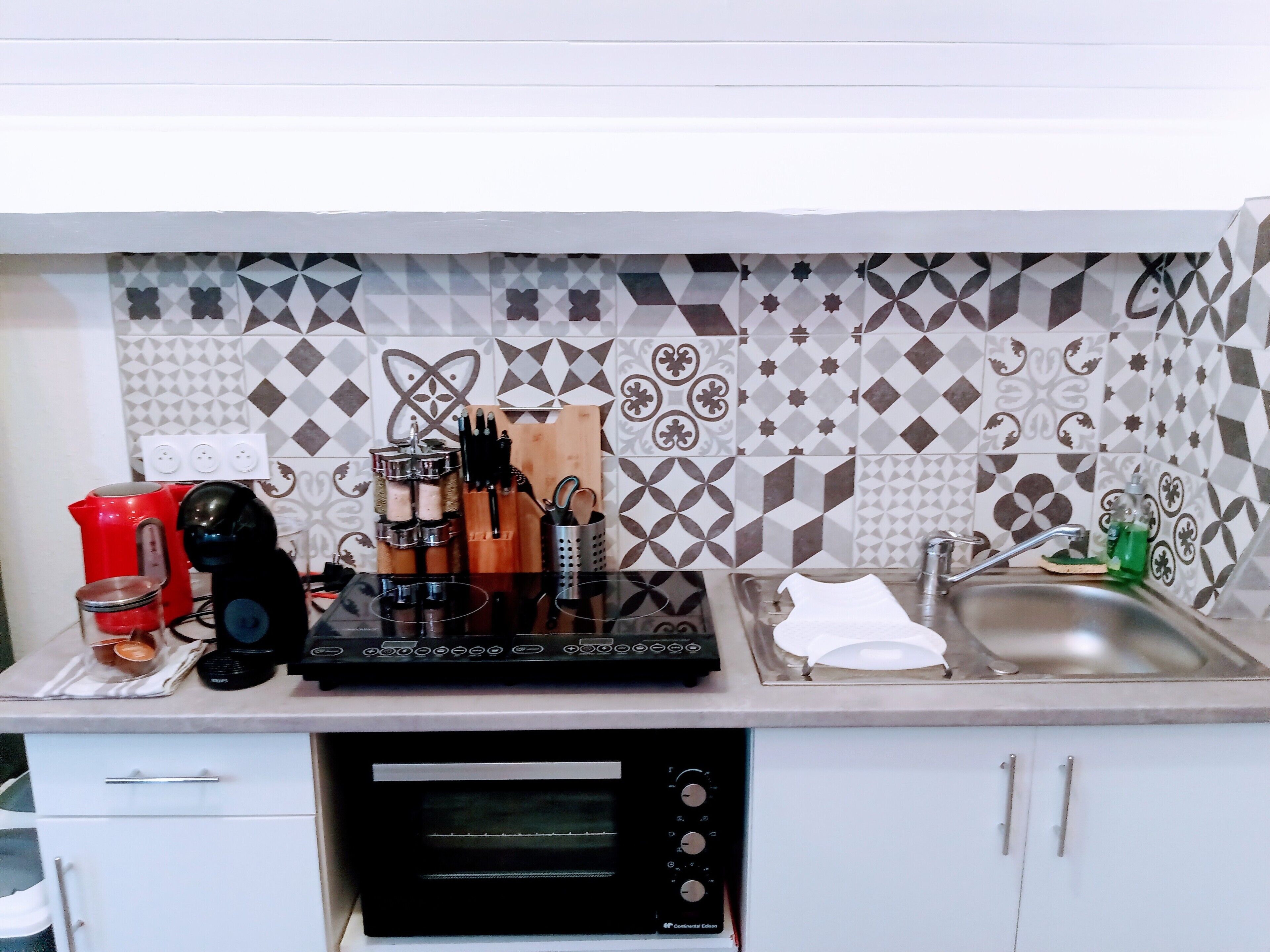 Uma cozinha com micro-ondas, cafeteira e diversos utensílios sobre o balcão.
