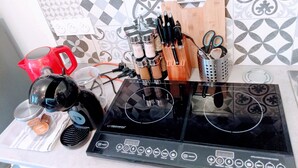 A kitchen with a black induction cooktop, a red kettle, and various kitchen utensils. - Casa Azur - Charming Palois studio with free parking 24/24 (Pau)