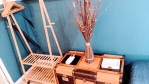 A wooden easel with a metal stand, a vase with dried plants, and a vintage suitcase with a metal latch. - Casa Azur - Charming Palois studio with free parking 24/24 (Pau)