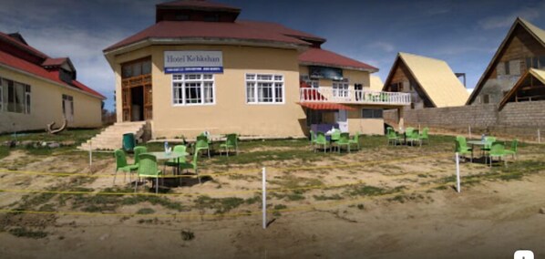 Hotel Kathibahan features a unique red roof and a balcony, offering a comfortable outdoor seating area with green chairs.