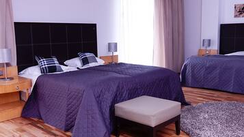 Habitación de hotel con dos camas, un banco y una alfombra pequeña.
