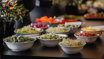 A buffet table with various dishes including salads, vegetables, and other food items.