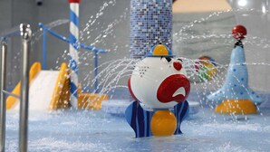 Un área de juegos acuáticos con un gran personaje inflable, chorros de agua y estructuras de juego coloridas.