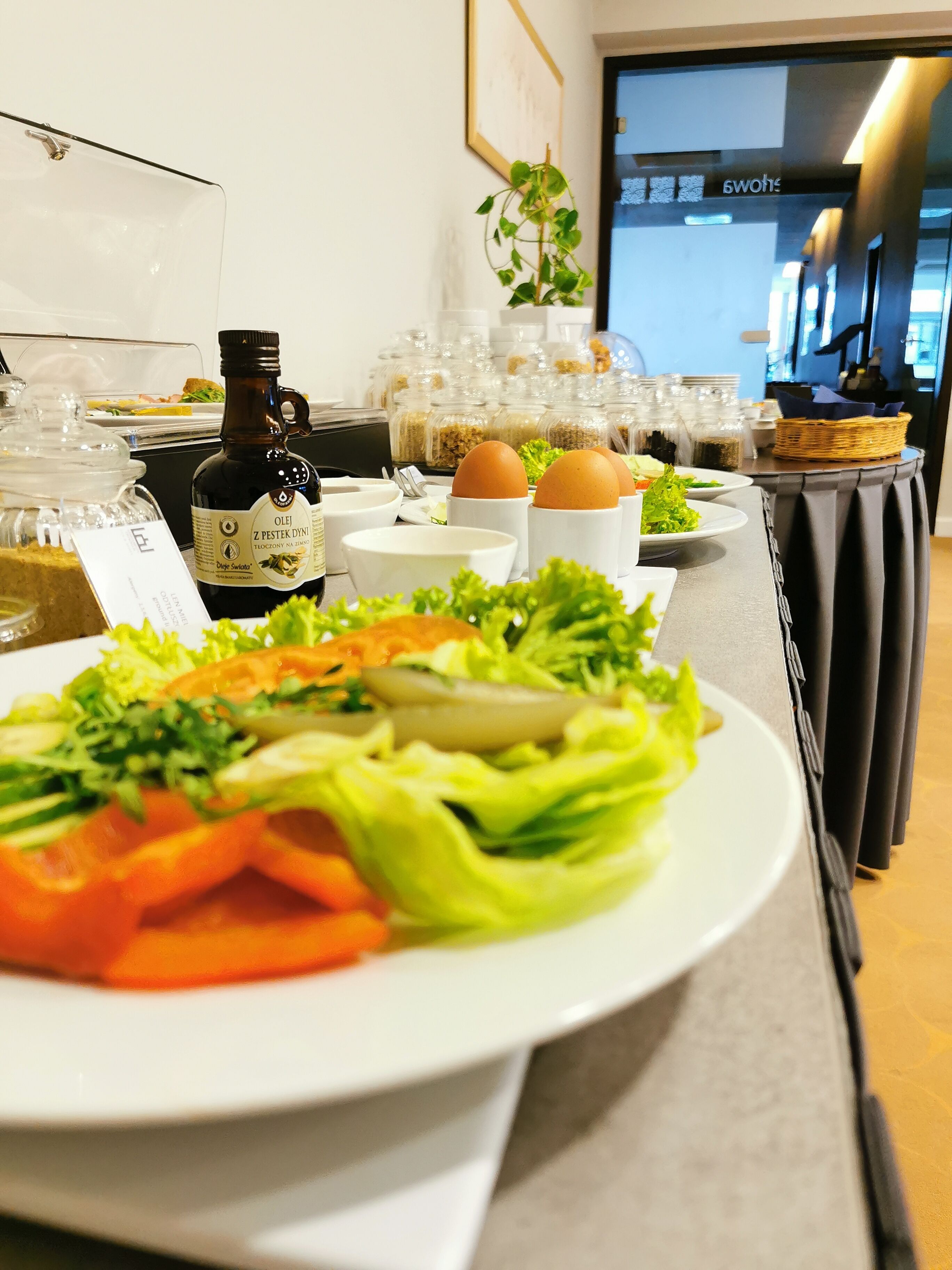A buffet table with various dishes, including salads and eggs, and a bottle of olive oil.