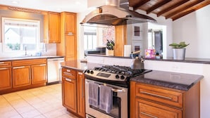 Une cuisine avec des meubles de rangement en bois, une cuisinière et une grande fenêtre.